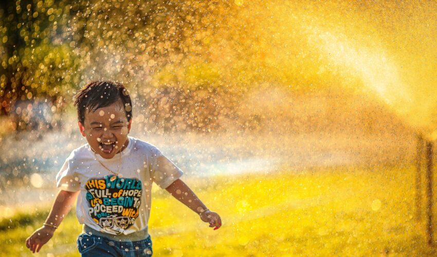 young boy running through sprinkler