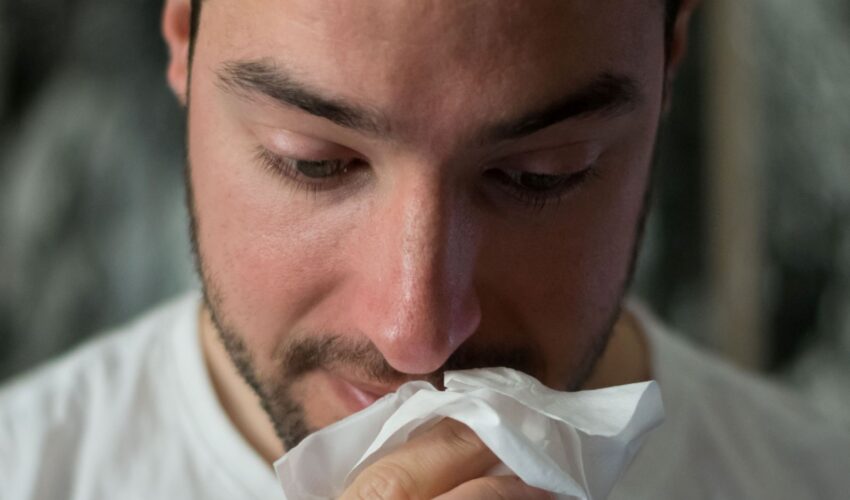 man wiping his nose with a tissue